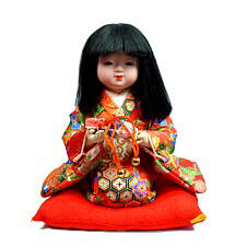 японская кукла Девочка, сидящая на красной шелковой подушечке